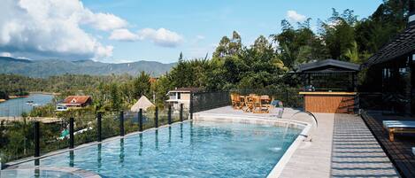 A swimming pool with a view of mountains and a lake.