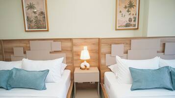 Une chambre d’hôtel avec deux lits, une table de chevet avec une lampe et deux tableaux encadrés au mur.
