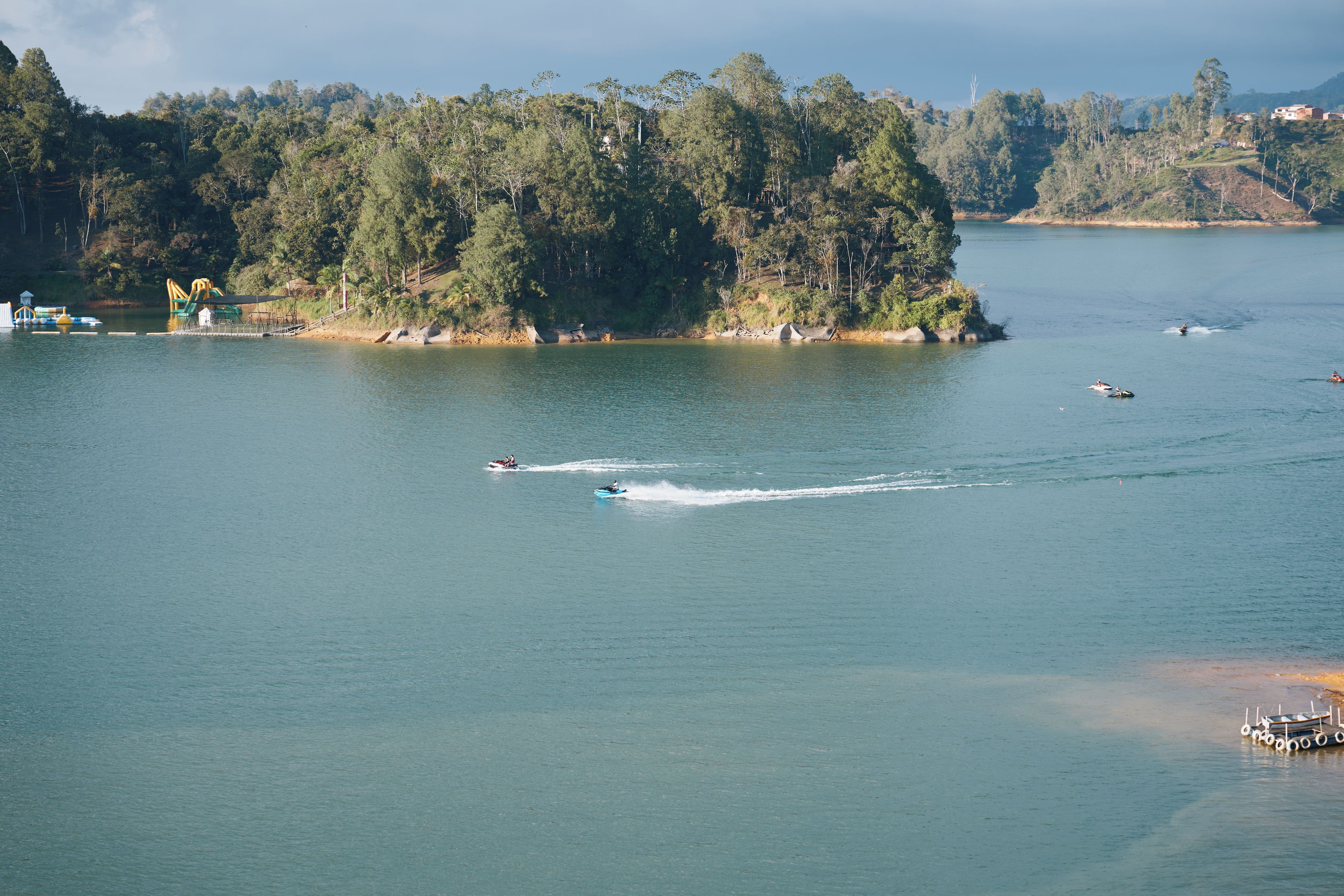 A lake with boats, a dock, and a forested island.