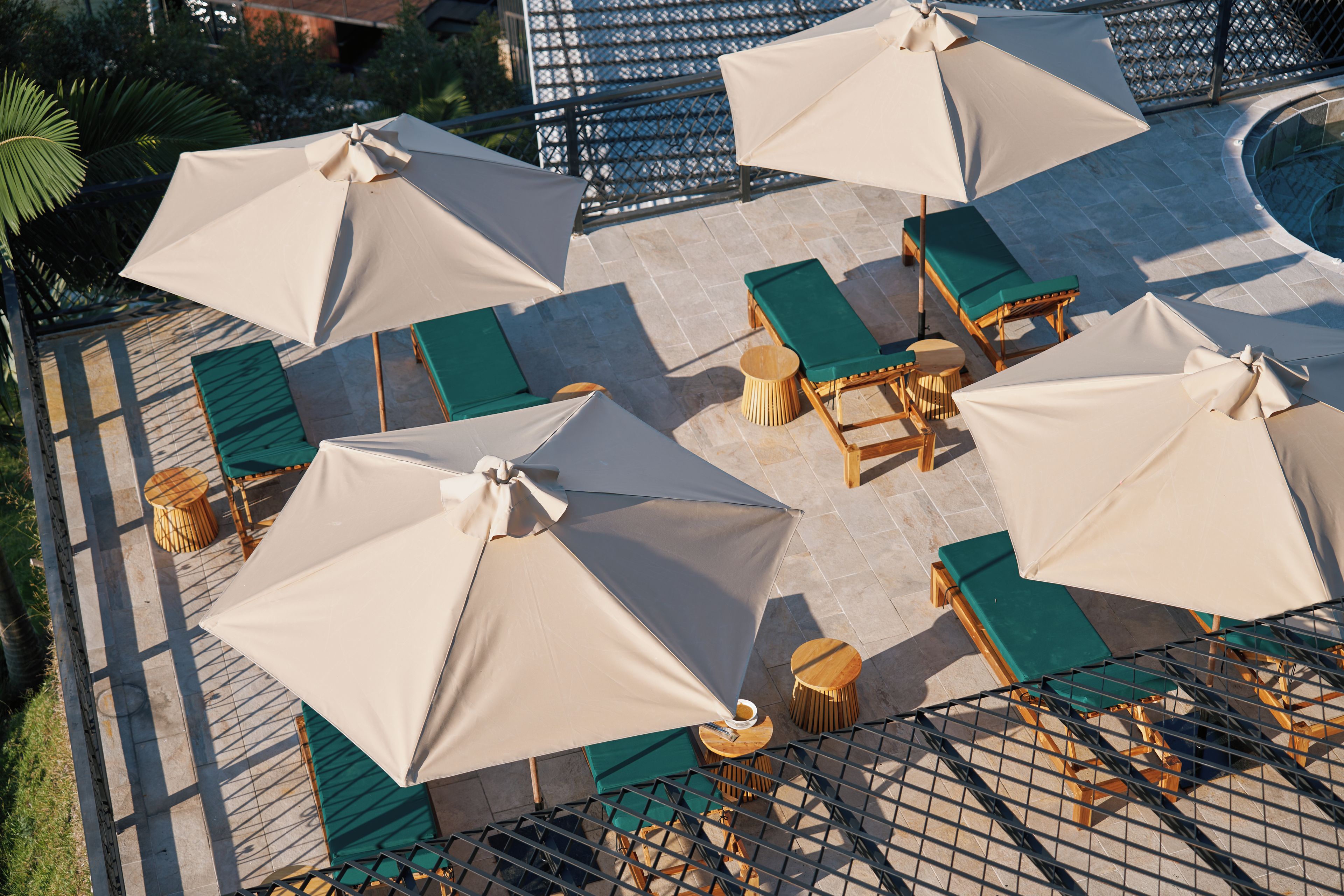 Una terraza en la azotea con varias zonas de descanso, cada una con una mesa y una silla, y varios sombrillas grandes que brindan sombra.