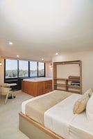 Un dormitorio con una cama grande, un escritorio y vistas a un paisaje natural.