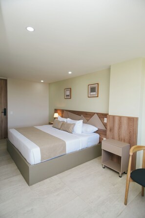Une chambre d’hôtel avec un grand lit, des tables de chevet, une chaise et une petite table.