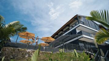 Een modern gebouw met een balkon, buiten parasols en een trap erheen.
