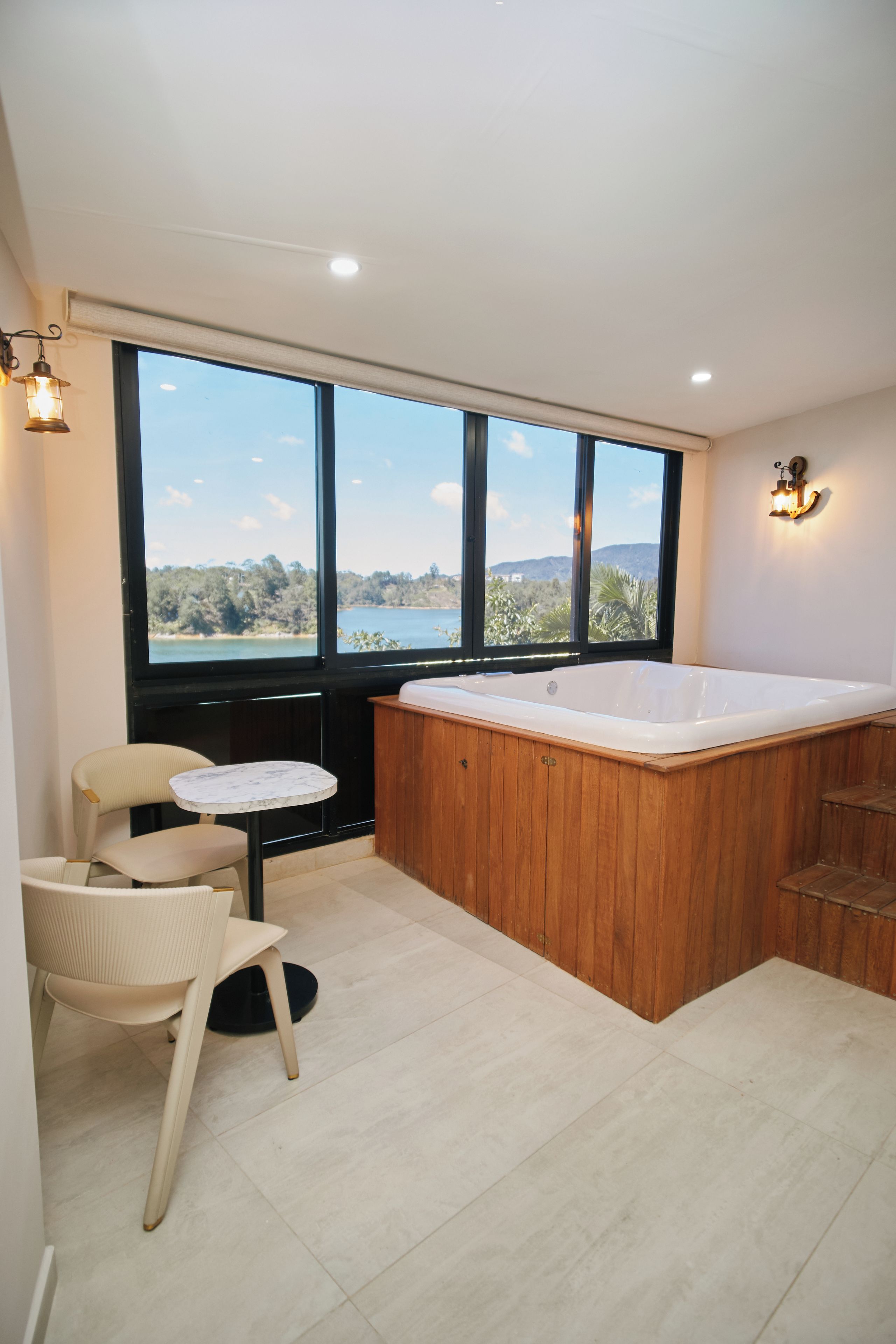 Ein modernes Badezimmer mit großem Fenster, einer Holzwanne und einem kleinen Tisch mit Stühlen.