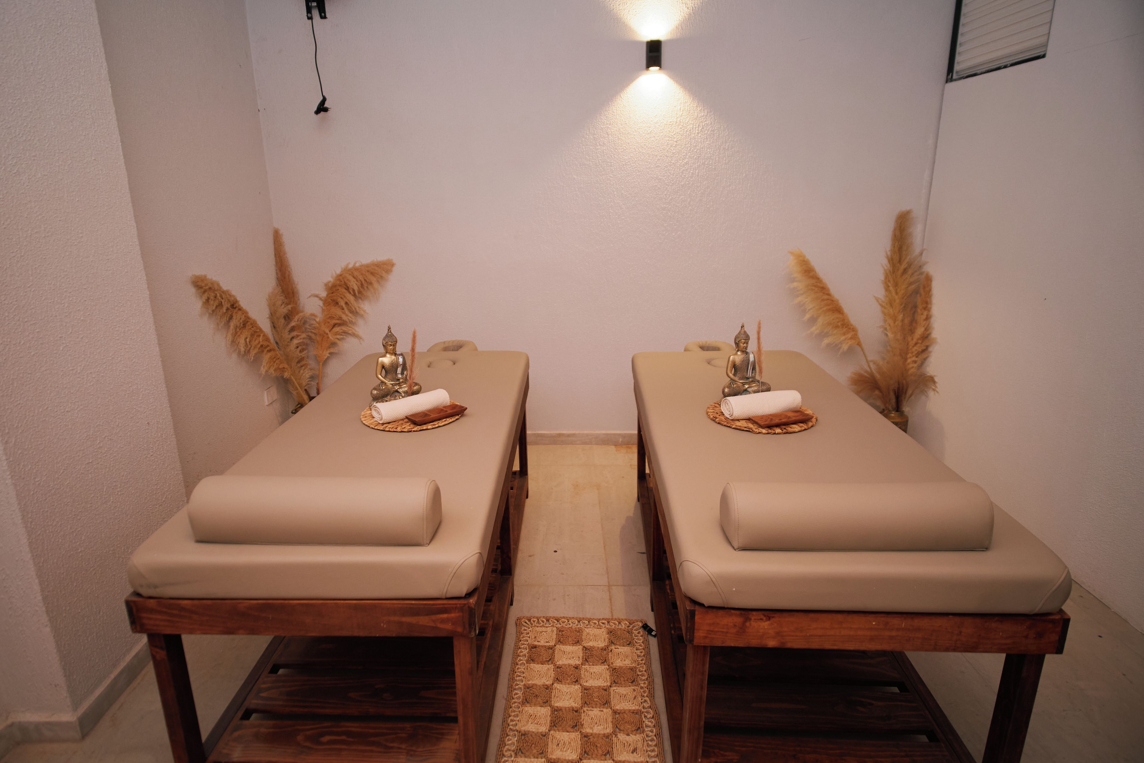 Une pièce comprenant deux tables de massage, chacune étant équipée d’une serviette roulée et d’une petite statue.