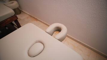 A room with a white examination table, a white cushioned headrest, and a wooden bench.