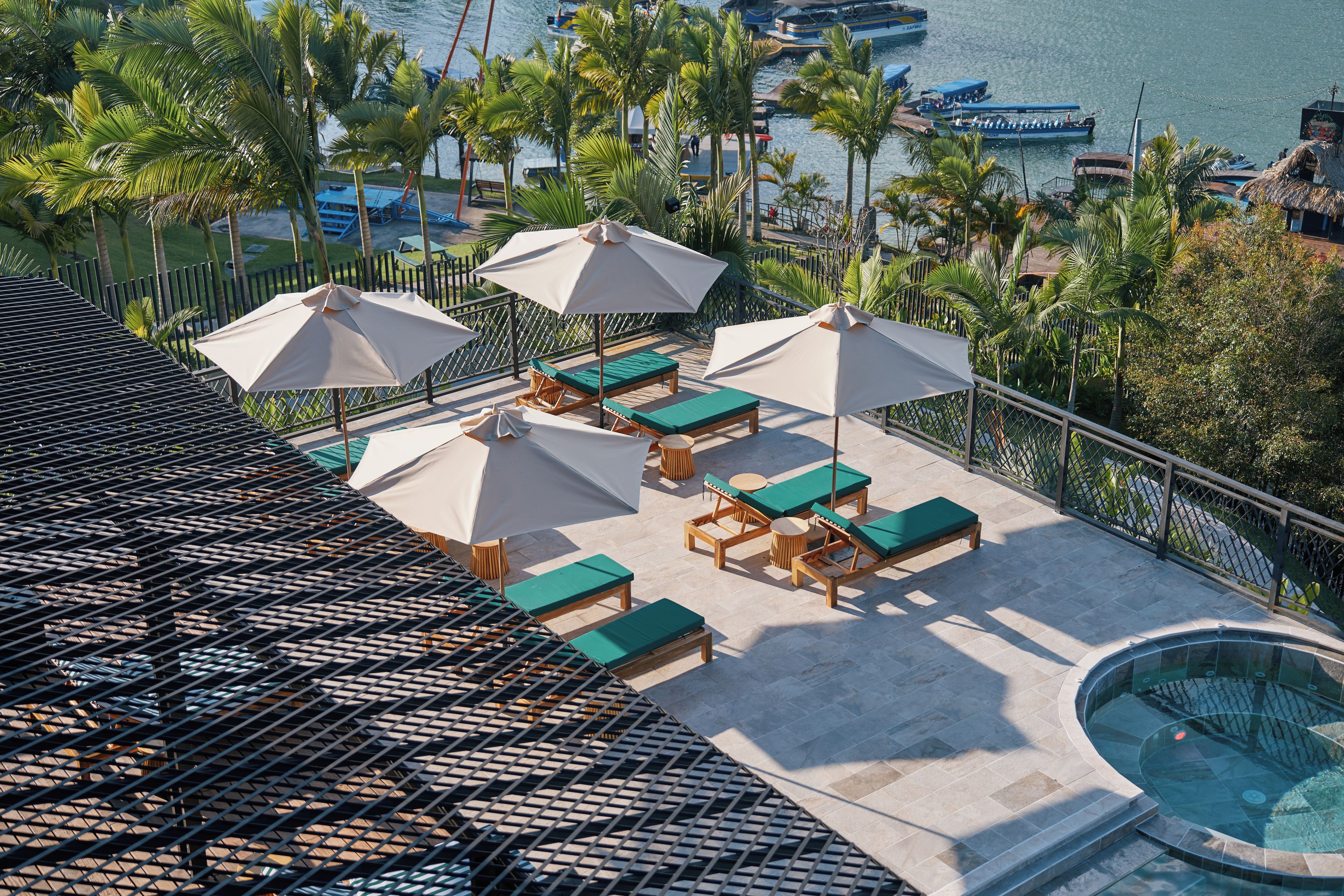 A rooftop pool area with lounge chairs and umbrellas, overlooking a marina with boats.