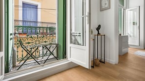 A corridor with a wooden floor, a green door, and a view of a balcony with a blue door and a green railing. - Le Foch - Bel appt moderne à 20 min de la plage (Béziers)
