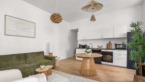 A modern living room with a green sofa, a round wooden coffee table, and a white rug. - Le Foch - Bel appt moderne à 20 min de la plage (Béziers)