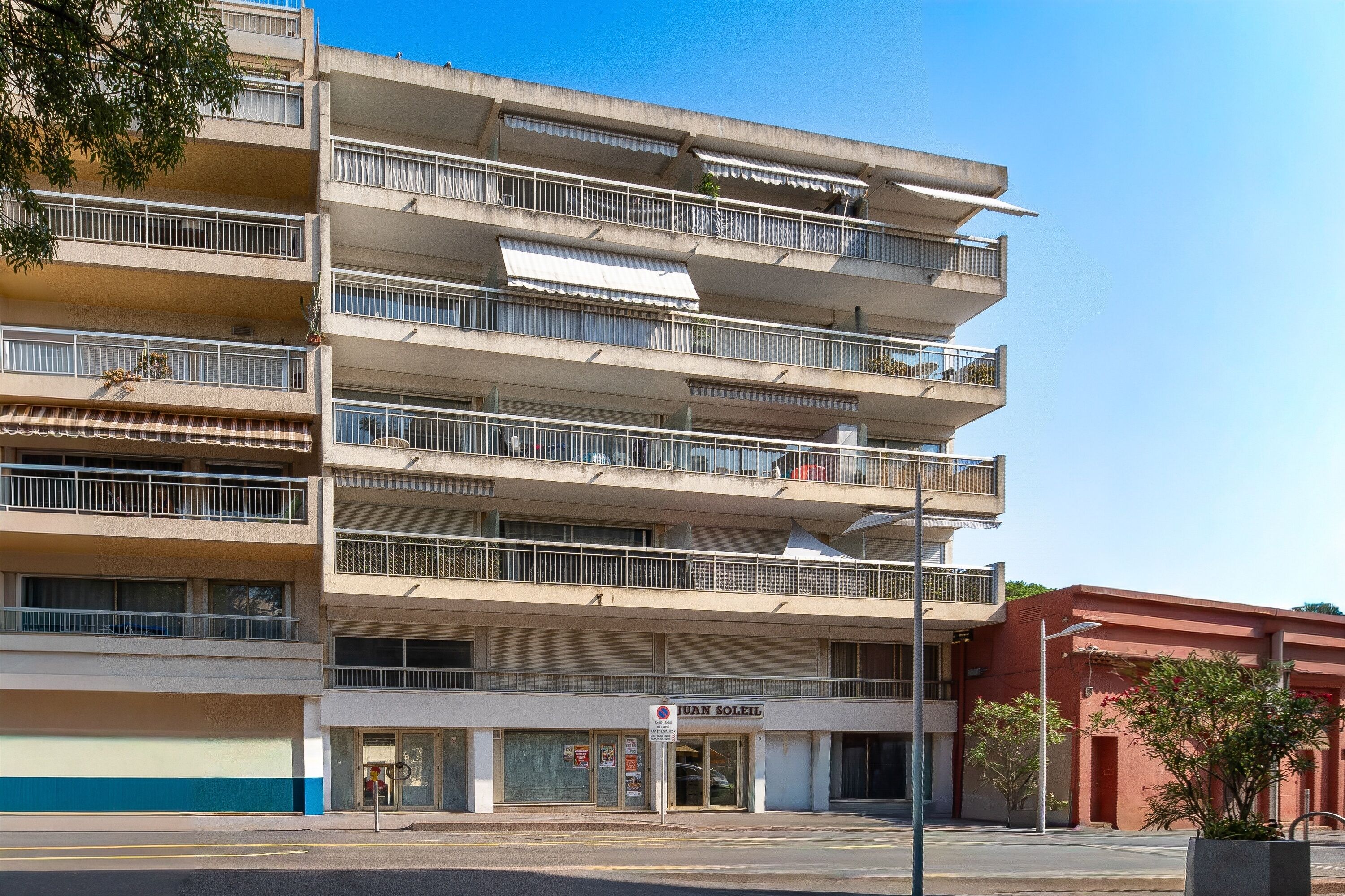 A multi-story building with balconies, a storefront, and a clear sky.
