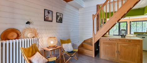 Un interior acogedor con una escalera de madera, un comedor con sillas y una mesa, y una zona de cocina con armarios.