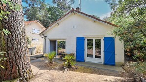 A single-story house with a sloped roof, a front door, and a small patio area. - Les Muguets - Maison familiale à 5 min de la plage (Sainte Brevin-les-Pins)