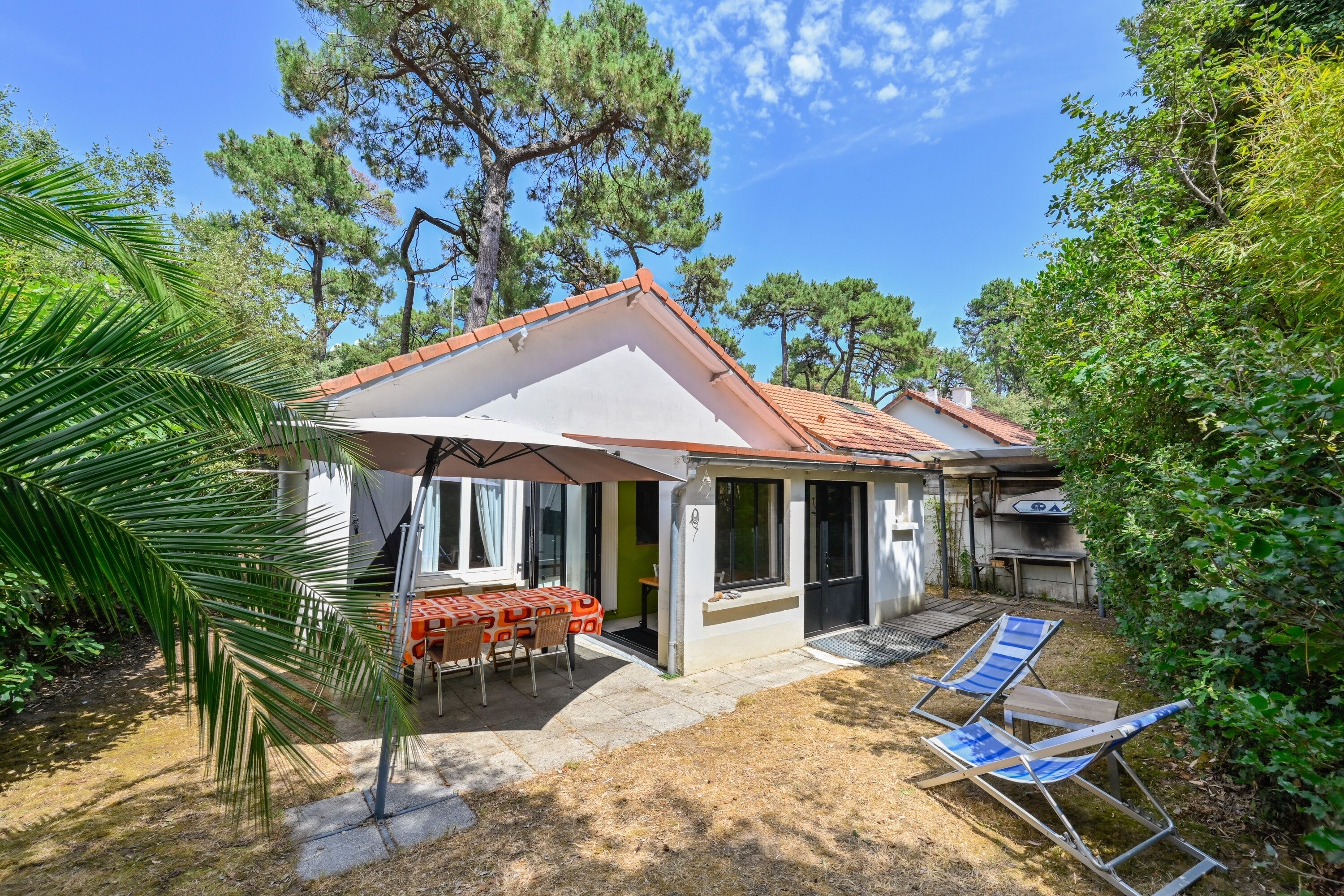 Ein Haus mit Terrasse, Grillplatz und einer Hängematte.