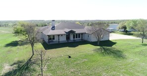 A single-story house with a covered porch and a large lawn.