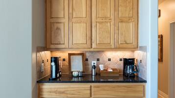 A kitchen with wooden cabinets, a marble backsplash, and a coffee station with multiple coffee makers.