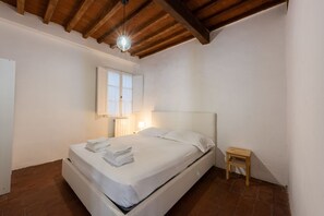 A bedroom with a single bed, a small wooden stool, a nightstand with a lamp, and a window with curtains. - Ruote Nest by MMega Homes and Villas  (Florence)