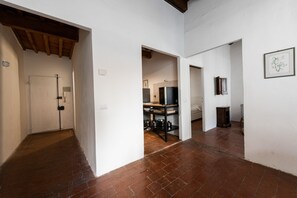 A hallway with a tiled floor, a white door, and a kitchen area with a refrigerator and shelves. - Ruote Nest by MMega Homes and Villas  (Florence)