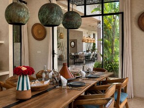 A dining area with a long wooden table set for a meal, surrounded by chairs. - Palais Samalya (Bouzama)