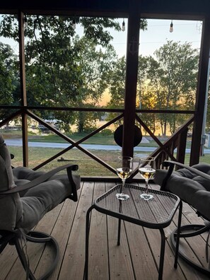 A covered outdoor seating area with a view of a lake and trees.