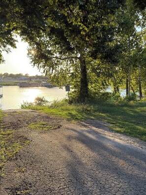 A gravel path leading to a body of water with a bridge in the distance. - The Cabin on Monkey Island (Afton)