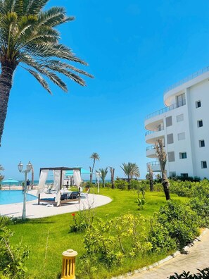 A resort with a pool, outdoor seating, and a building with balconies.