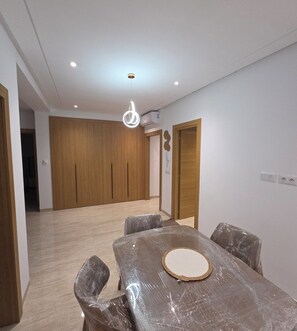 A room with a dining table, chairs, a ceiling light, and wooden doors.