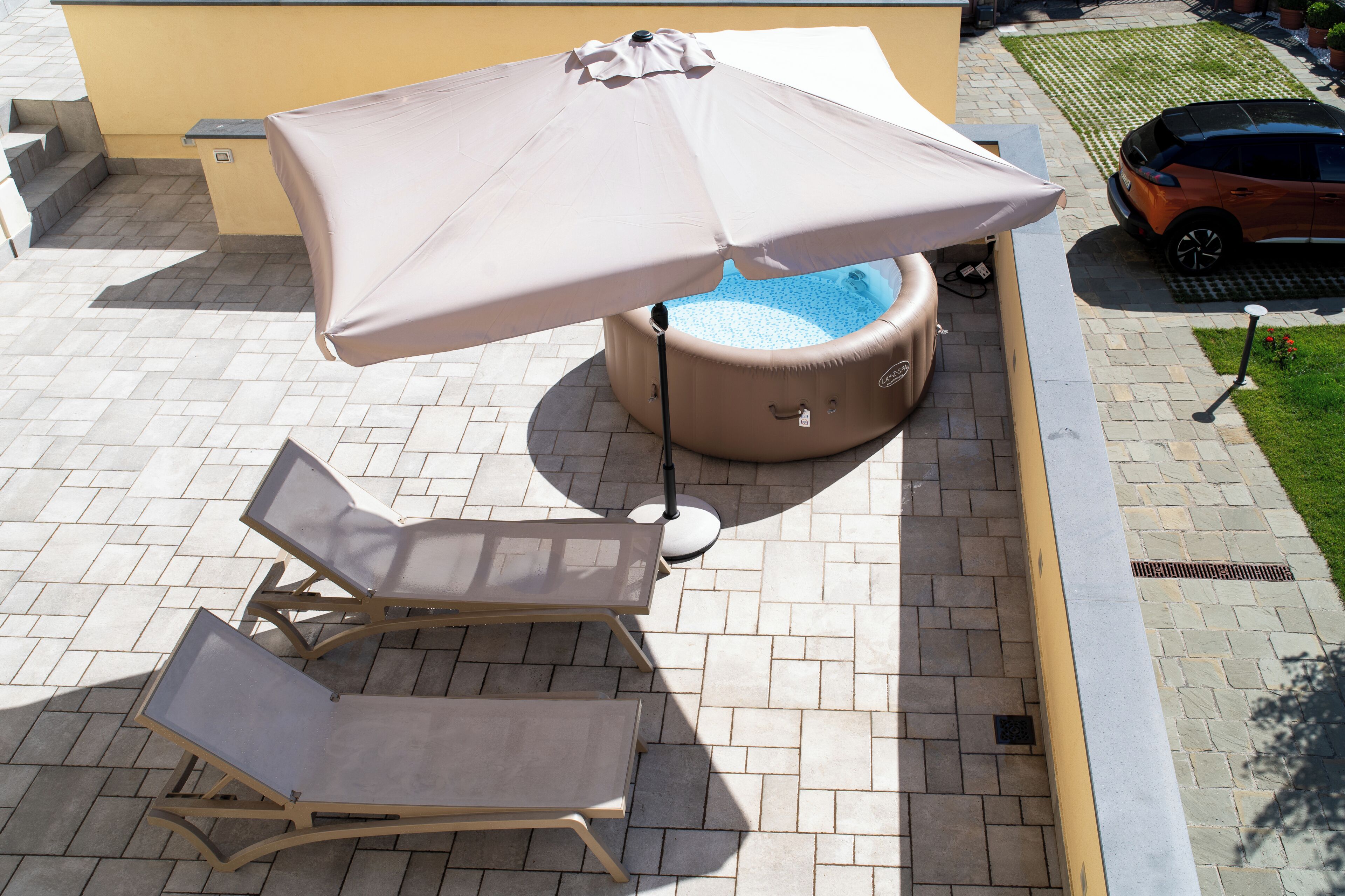A patio area with a hot tub, lounge chairs, and an umbrella.