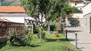 A garden with a tree, a wooden fence, and a stone wall. - De Vivo Realty - Villa Colomba (Ticciano)