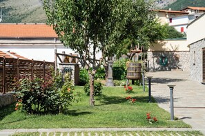 A garden with a tree, a wooden fence, and a stone wall. - De Vivo Realty - Villa Colomba (Ticciano)