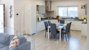 A modern kitchen with a dining area, a sofa, and a window with a view. - De Vivo Realty - Villa Colomba (Ticciano)