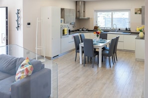 A modern kitchen with a dining area, a sofa, and a window with a view. - De Vivo Realty - Villa Colomba (Ticciano)