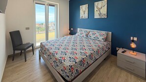 A bedroom with a bed, a chair, a nightstand, and artwork on the wall. - De Vivo Realty - Villa Colomba (Ticciano)