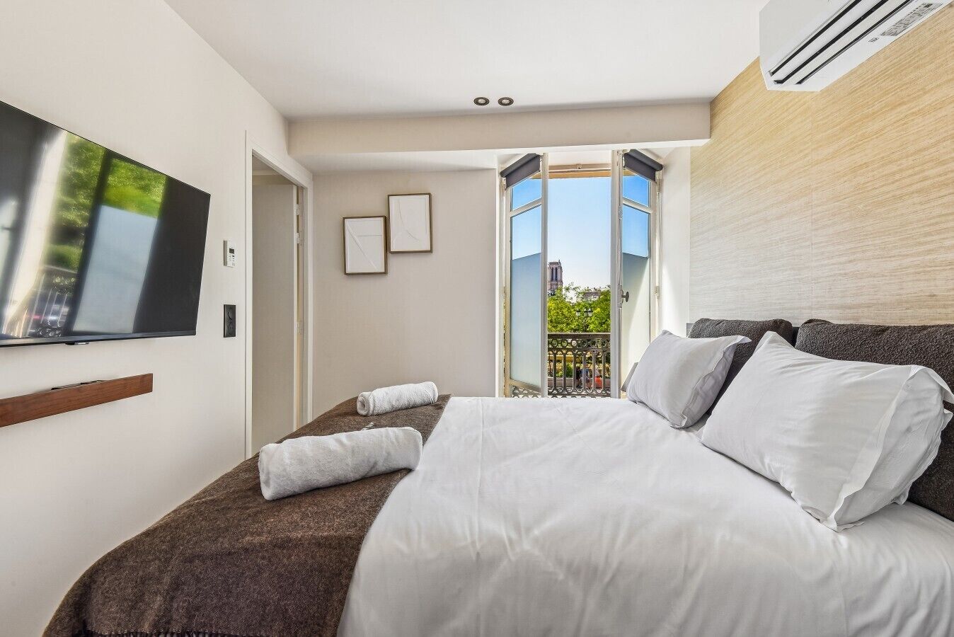 Ein Hotelzimmer mit Bett, Fernseher, einem Balkon mit Blick und einem Fenster.