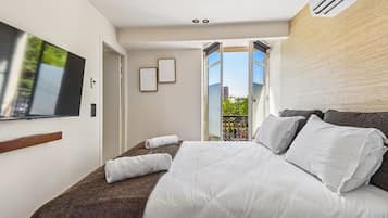 Una habitación de hotel con cama, televisión, balcón con vistas y ventana.