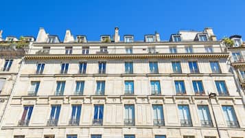 Un edificio de varios pisos con un estilo arquitectónico clásico, que presenta una fachada simétrica con ventanas regularmente distribuidas y molduras decorativas.