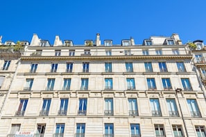 Ein mehrgeschossiges Gebäude im klassischen Stil, mit einer symmetrischen Fassade, gleichmäßig verteilten Fenstern und dekorativen Gesimsen.