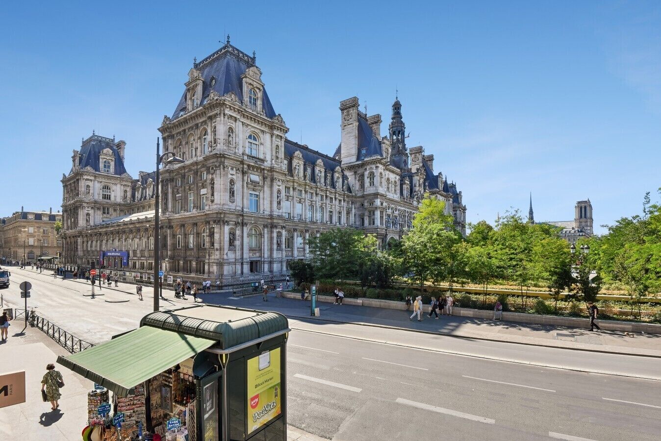 A historic building with classical architecture, a paved street, and a green area with trees.