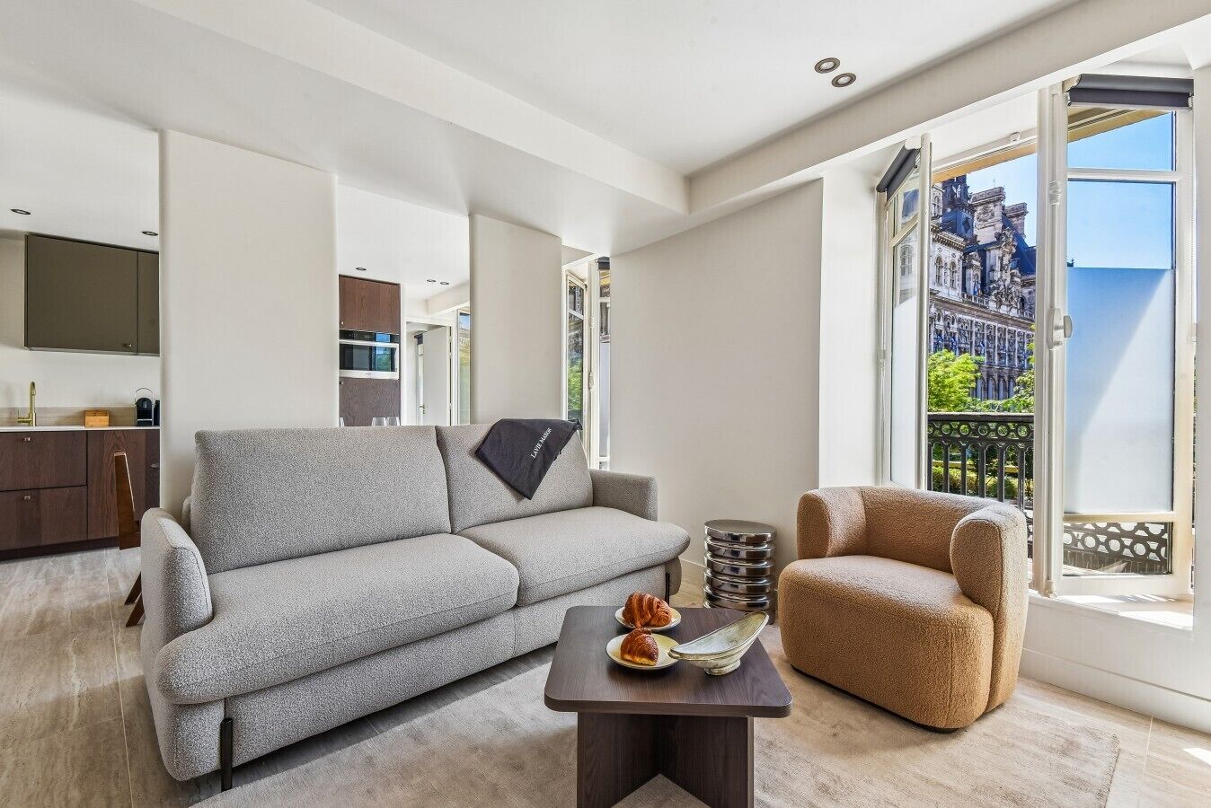 Un salon moderne avec un canapé gris, un fauteuil marron et une petite table agrémentée d’un objet décoratif.