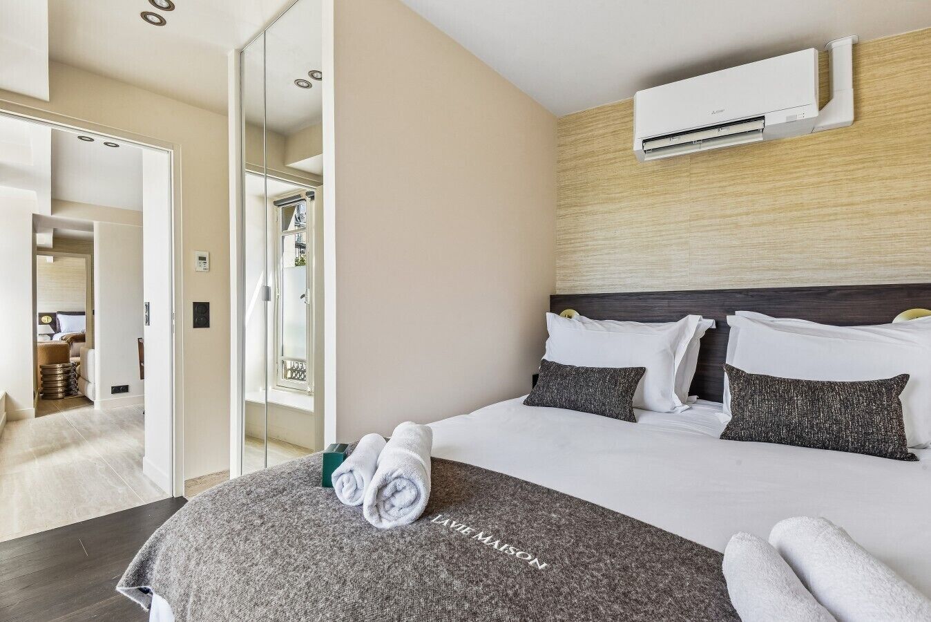Habitación de hotel con cama, espejo, aire acondicionado y vistas al exterior.
