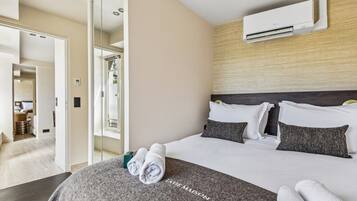 Habitación de hotel con cama, espejo, aire acondicionado y vistas al exterior.