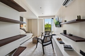 A modern living room with a sofa, a dining table, chairs, and a TV mounted on the wall. - Lavie Maison | Rivoli & Louvre (Paris)