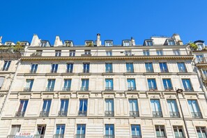 Ein mehrgeschossiges Gebäude im klassischen Stil, mit einer symmetrischen Fassade, gleichmäßig verteilten Fenstern und dekorativen Gesimsen.