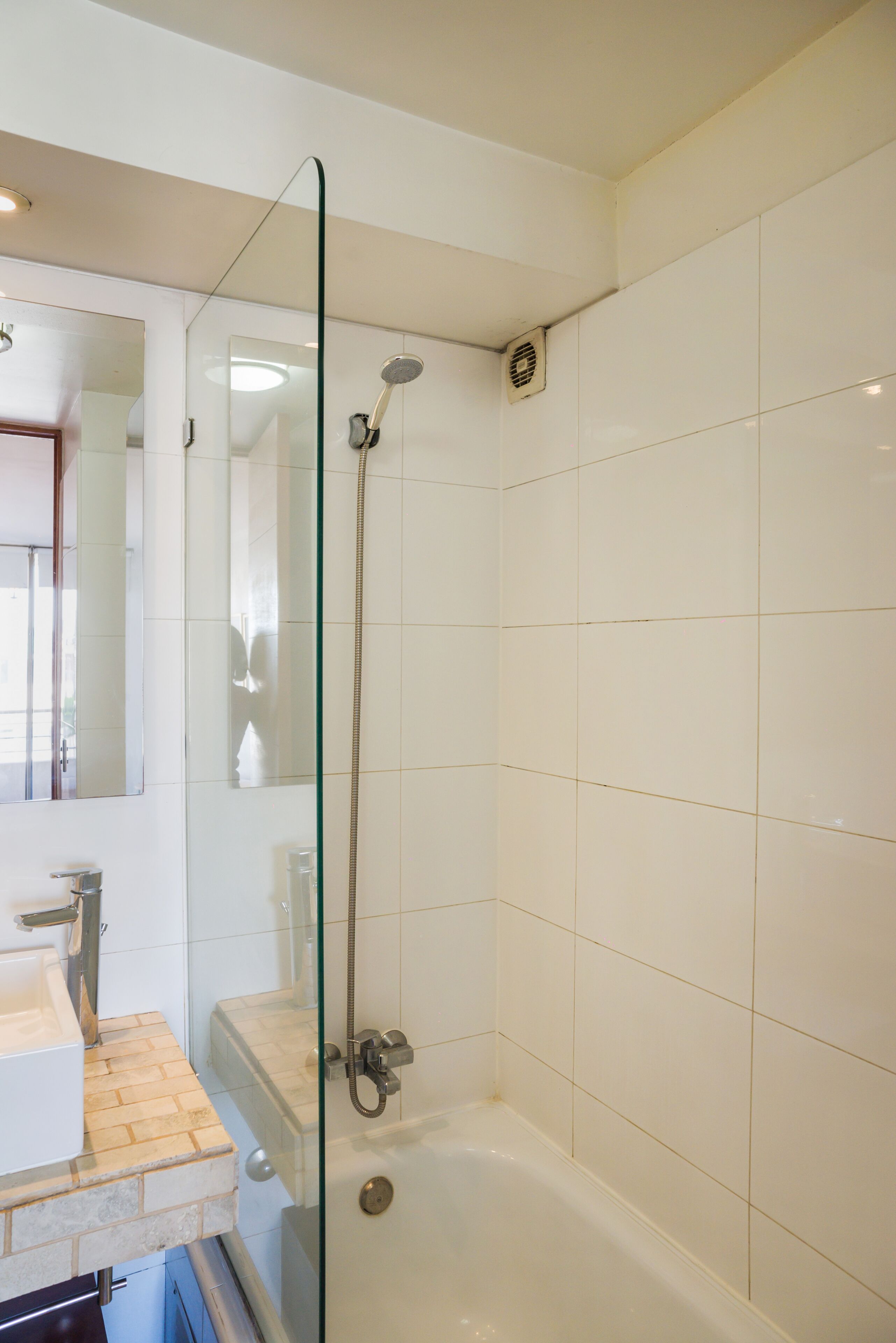Un bagno con doccia vetrata, lavandino e specchio.