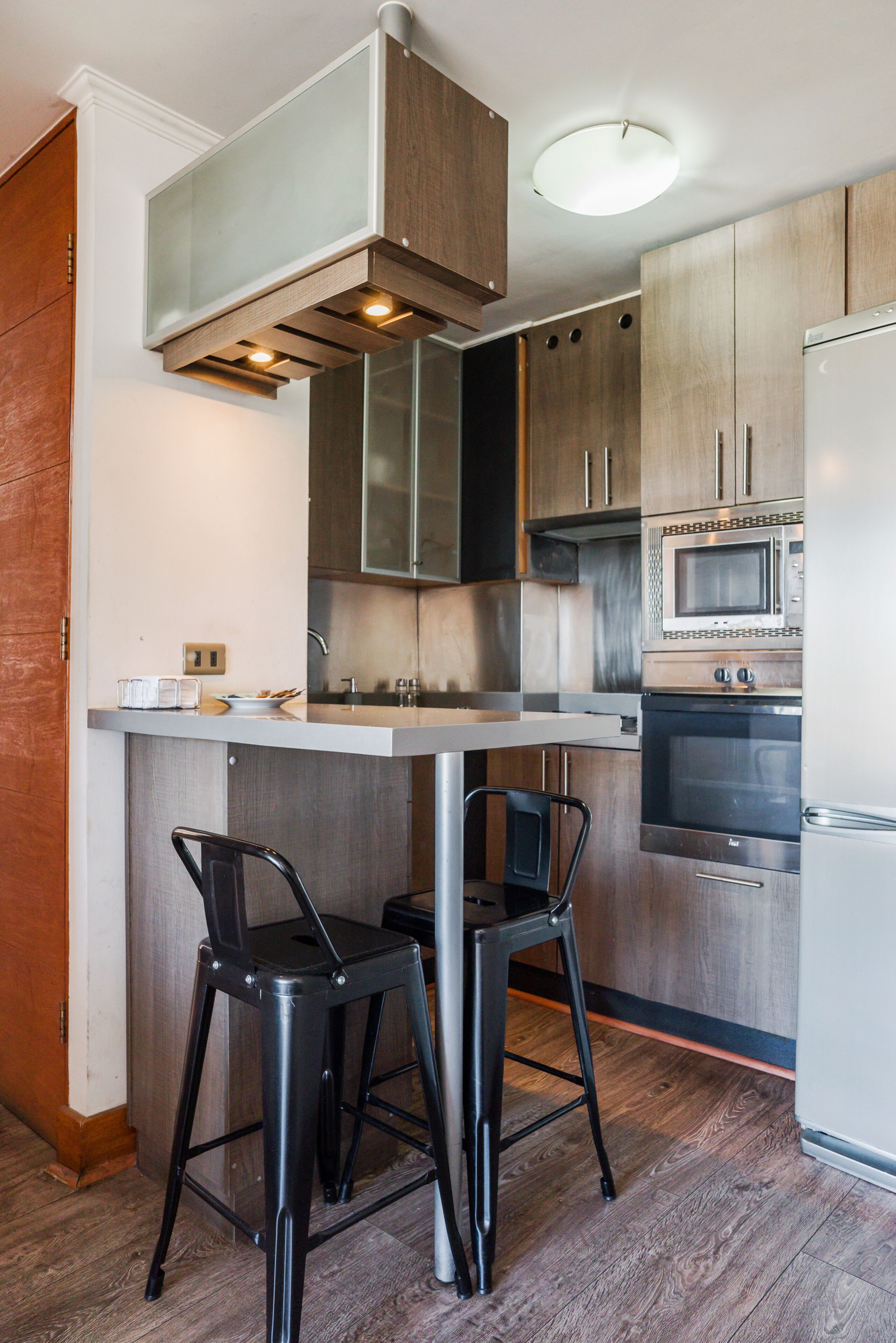 Una cocina moderna con una isla central, electrodomésticos de acero inoxidable y taburetes negros.