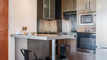 Una cocina moderna con una isla central, electrodomésticos de acero inoxidable y taburetes negros.