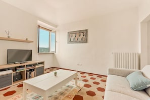 A modern living room with a flat-screen TV, a sofa, a coffee table, and a window with a view. - [SanVenerio] Sea view 5 TERRE (La Spezia)
