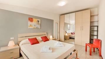 A modern bedroom with a large bed, bedside tables, a wardrobe, and a mirror.