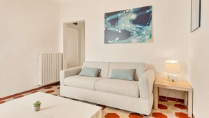 Un salon moderne avec un canapé, une petite table, une lampe et un tableau accroché au mur.