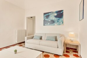 A modern living room with a sofa, a small table, a lamp, and a painting on the wall. - [SanVenerio] Sea view 5 TERRE (La Spezia)