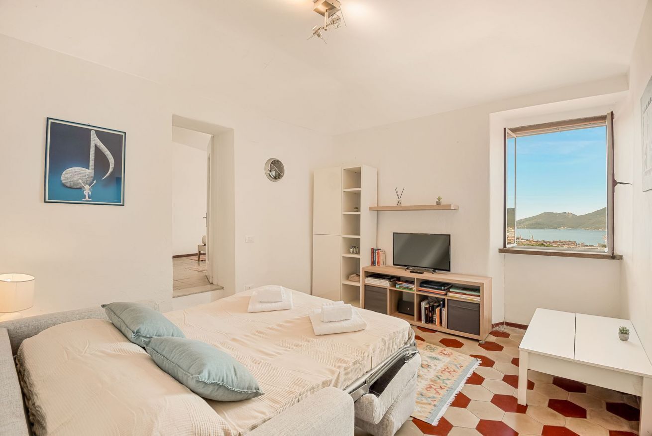 Habitación de hotel con cama, televisión, estantería, escritorio y ventana con vistas.